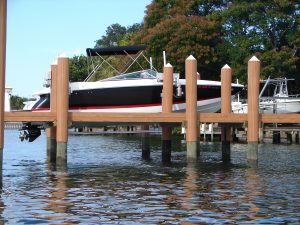 A speedboat lifted on a boat hoist off of a dock.