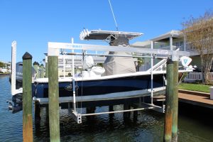 A cradle boat lift holding a blue and white v-hull boat.