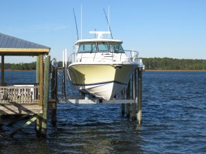 A cradle boat lift holding a boat with a yellowing hull.